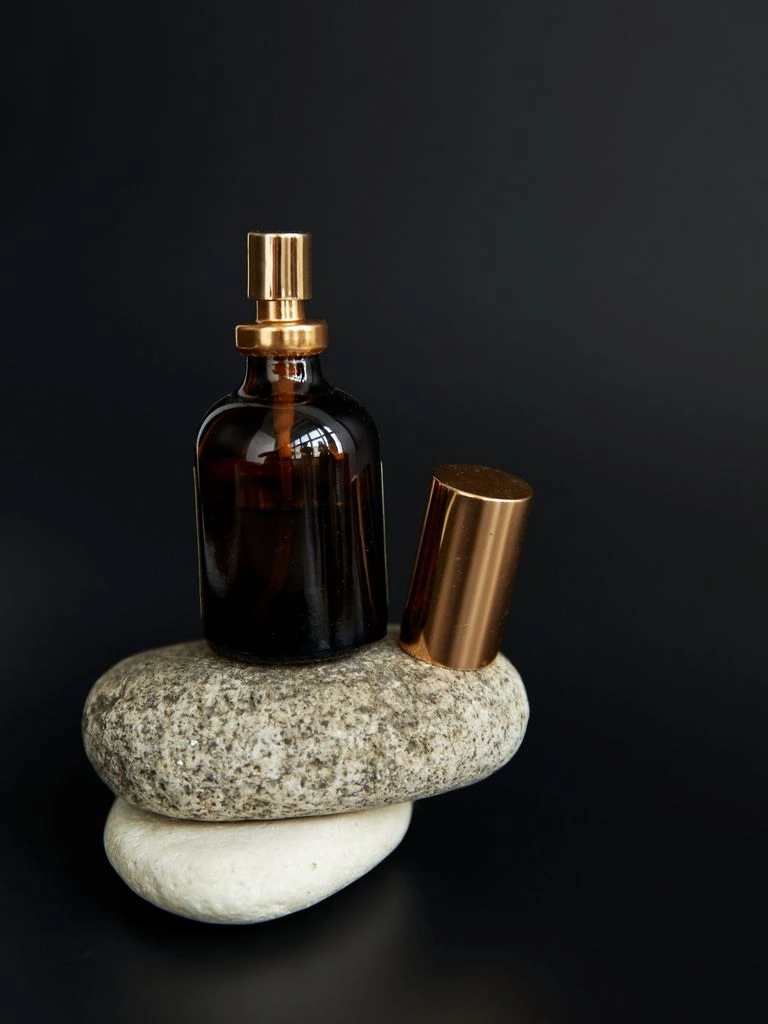 Amber glass beard oil bottle on cream surface, duotone treatment